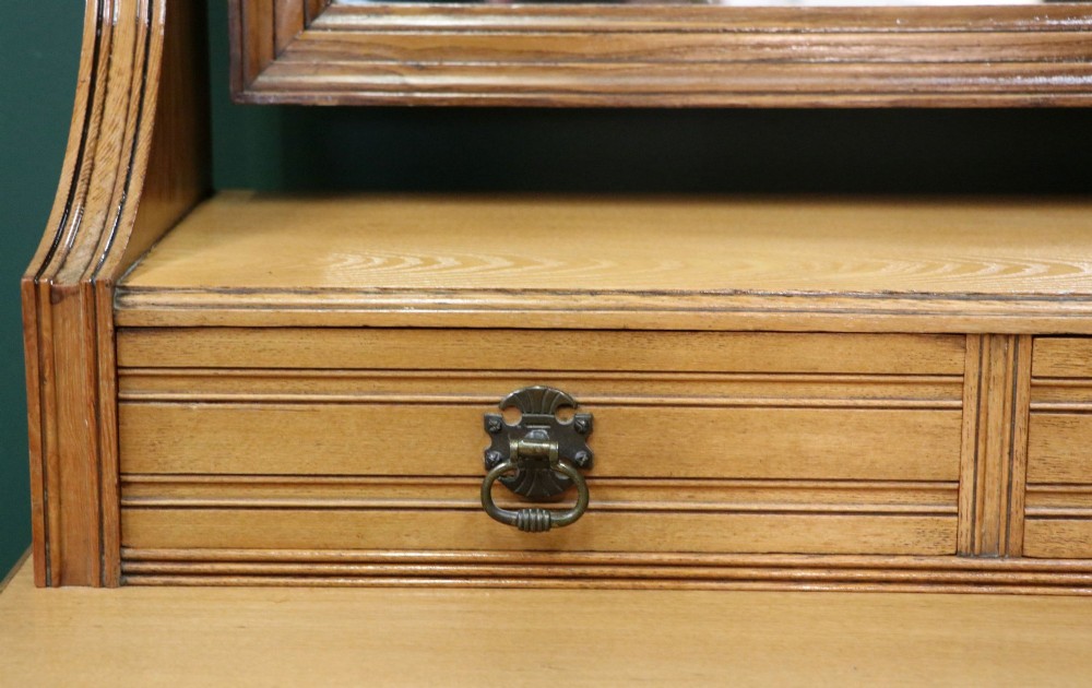 A late Victorian light walnut dressing table featuring an attached rectangular mirror, three small upper drawers, two panelled side cupboards, and turned legs with castors. View X