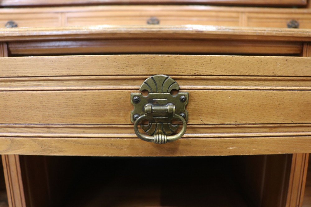 A late Victorian light walnut dressing table featuring an attached rectangular mirror, three small upper drawers, two panelled side cupboards, and turned legs with castors. View XI