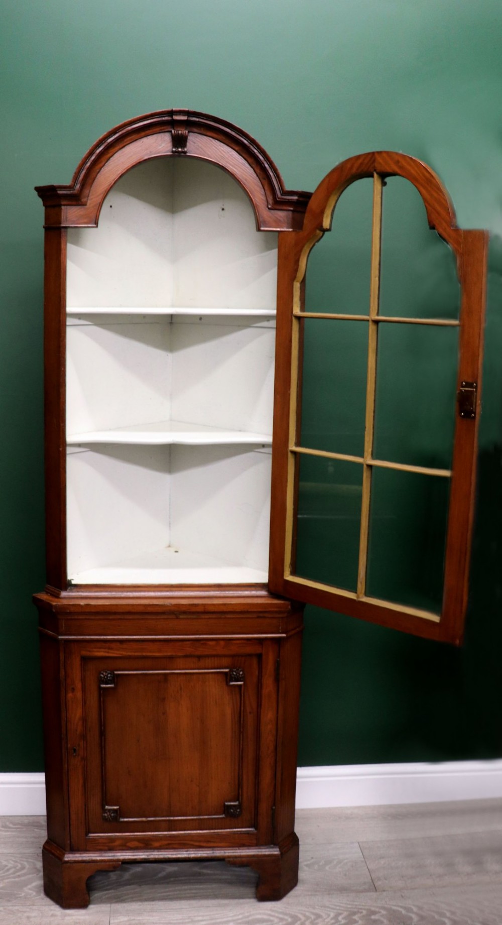 An early 20th-century floor-standing oak corner cabinet featuring an arched glazed upper door and a solid wood lower cupboard door. View II