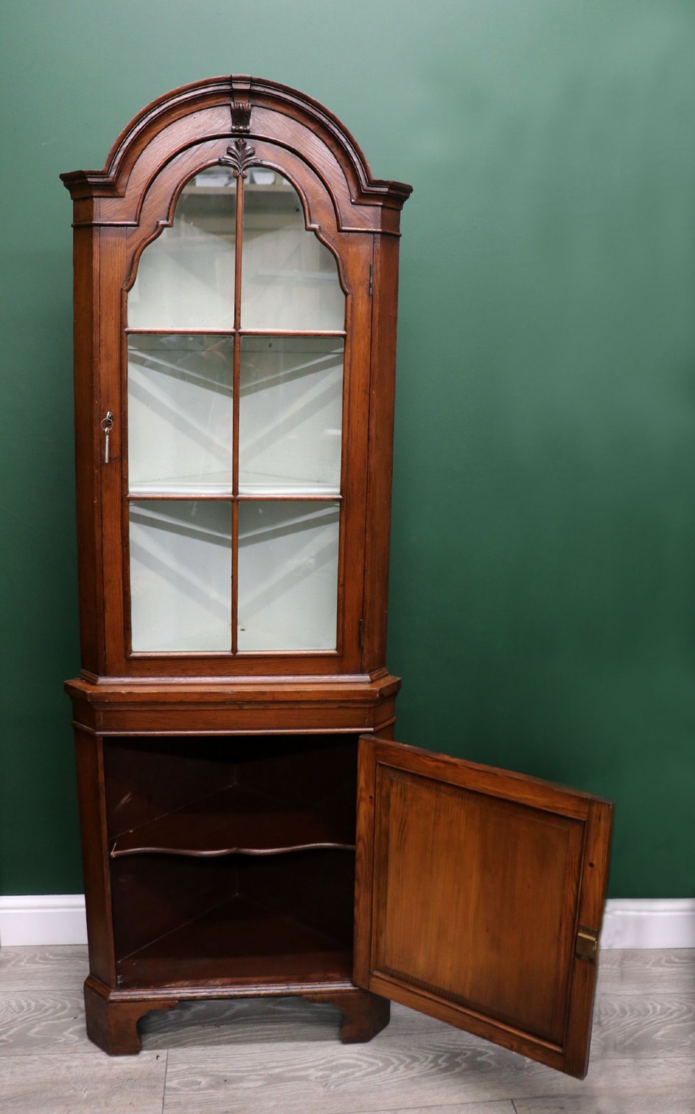 An early 20th-century floor-standing oak corner cabinet featuring an arched glazed upper door and a solid wood lower cupboard door. View III