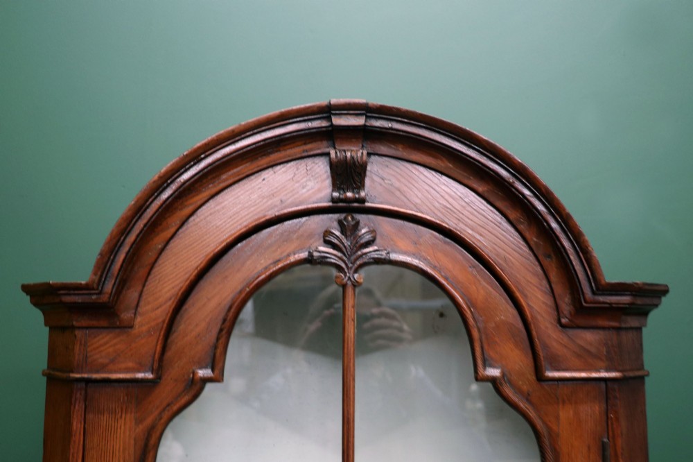 An early 20th-century floor-standing oak corner cabinet featuring an arched glazed upper door and a solid wood lower cupboard door. View V