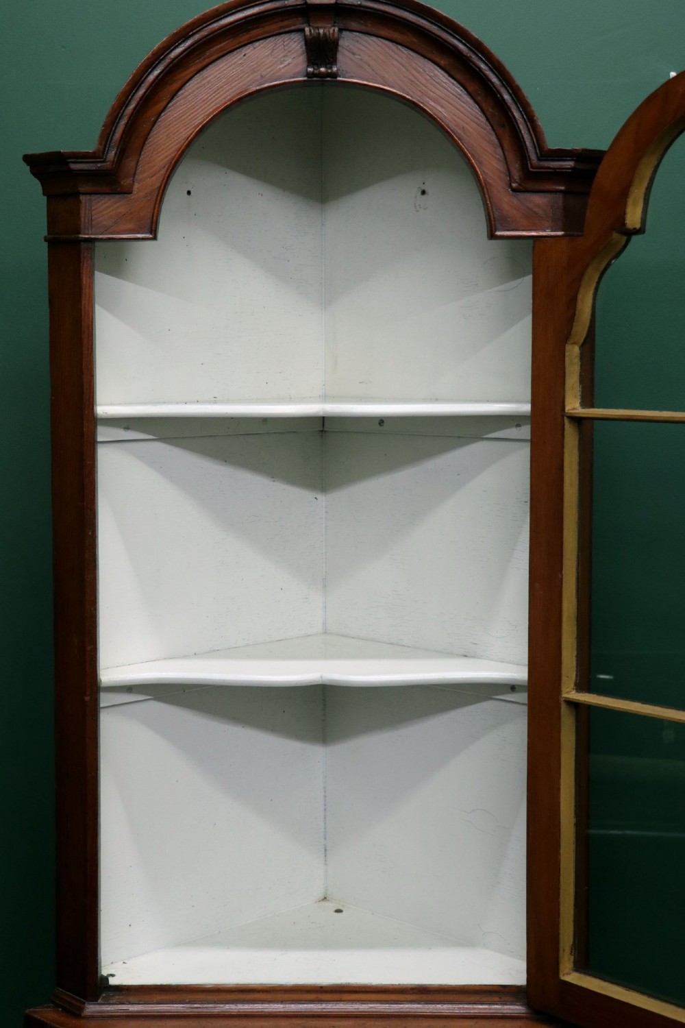 An early 20th-century floor-standing oak corner cabinet featuring an arched glazed upper door and a solid wood lower cupboard door. View VII