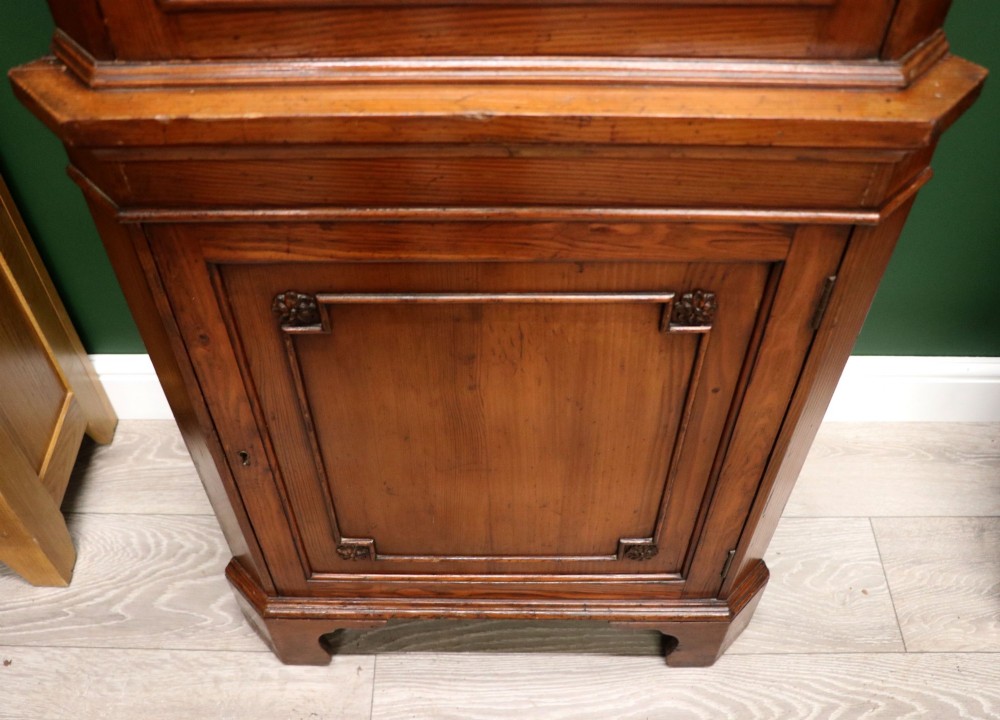 An early 20th-century floor-standing oak corner cabinet featuring an arched glazed upper door and a solid wood lower cupboard door. View X