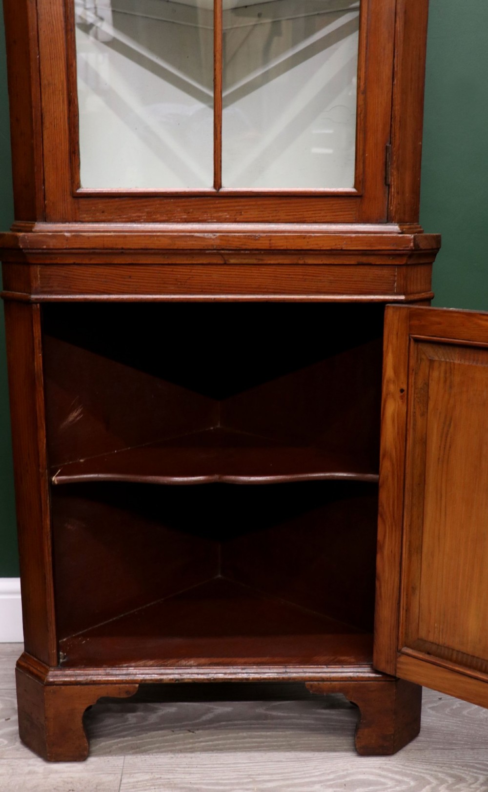 An early 20th-century floor-standing oak corner cabinet featuring an arched glazed upper door and a solid wood lower cupboard door. View XI
