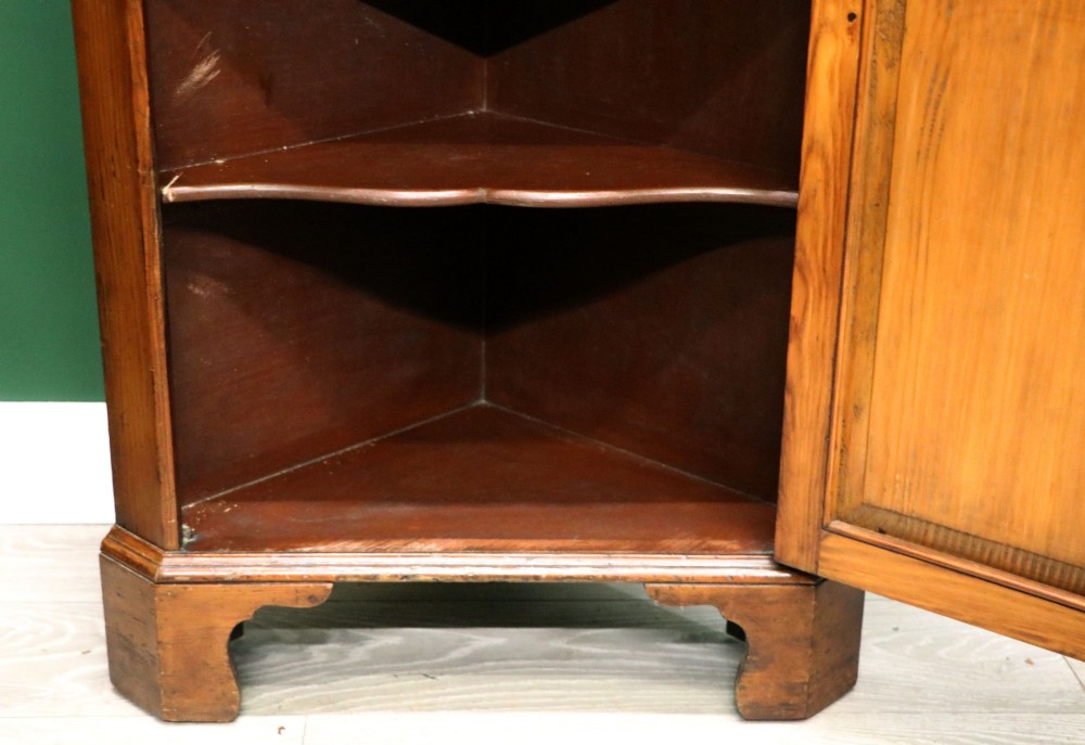 An early 20th-century floor-standing oak corner cabinet featuring an arched glazed upper door and a solid wood lower cupboard door. View XII