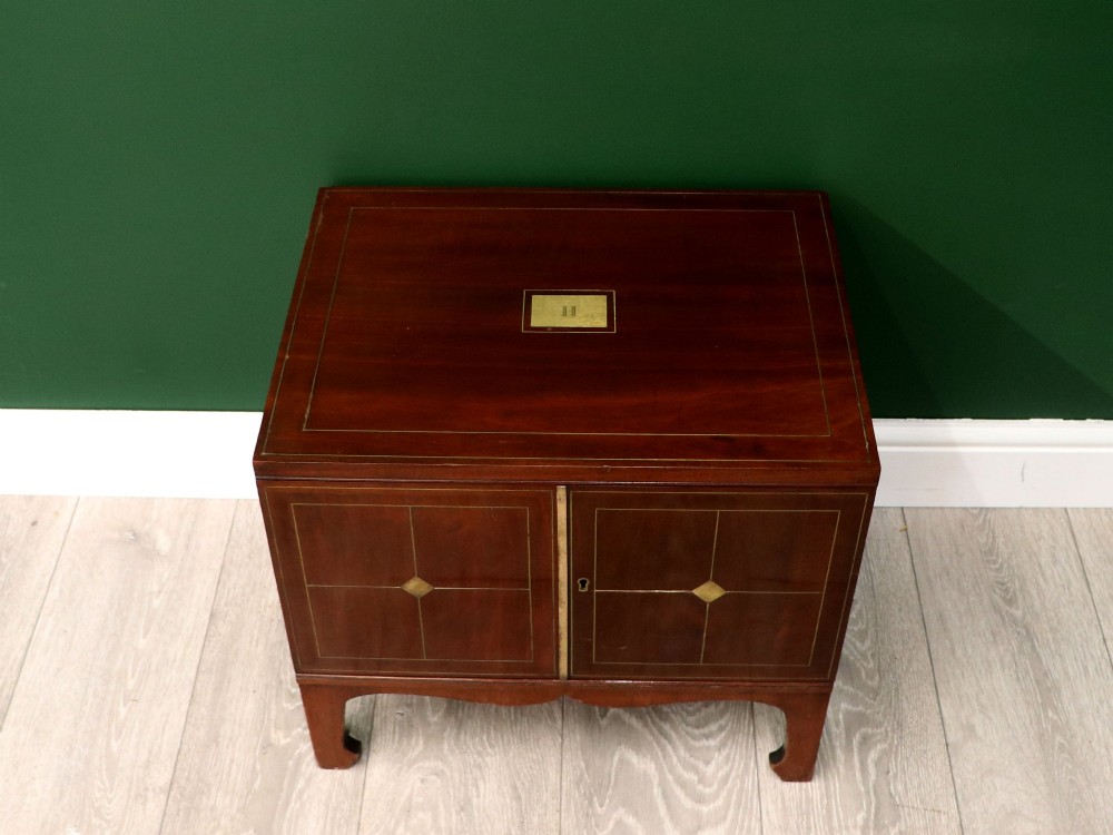 A mahogany campaign style collectors cabinet featuring geometric brass line inlays, twin front doors, a brass central keyhole, and shaped feet. View II