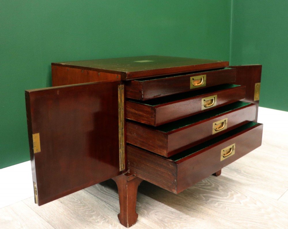 A mahogany campaign style collectors cabinet featuring geometric brass line inlays, twin front doors, a brass central keyhole, and shaped feet. View IV