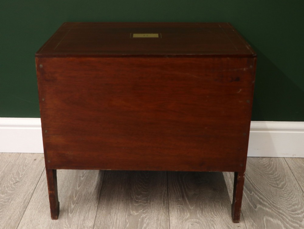 A mahogany campaign style collectors cabinet featuring geometric brass line inlays, twin front doors, a brass central keyhole, and shaped feet. View VI