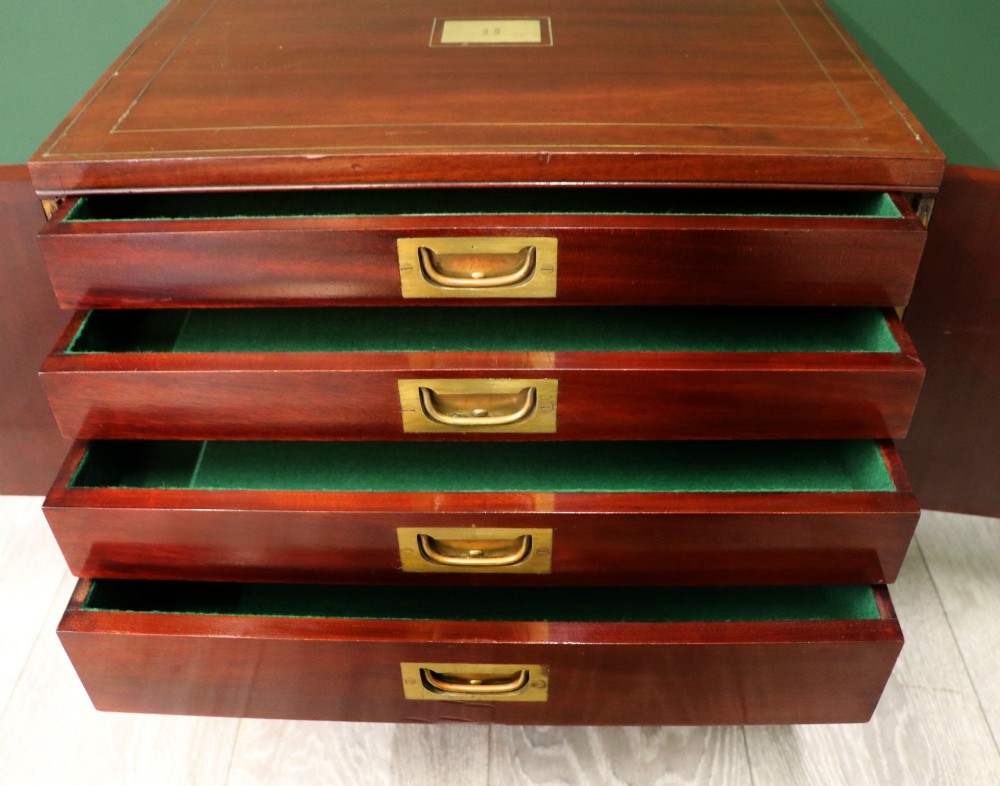 A mahogany campaign style collectors cabinet featuring geometric brass line inlays, twin front doors, a brass central keyhole, and shaped feet. View XII