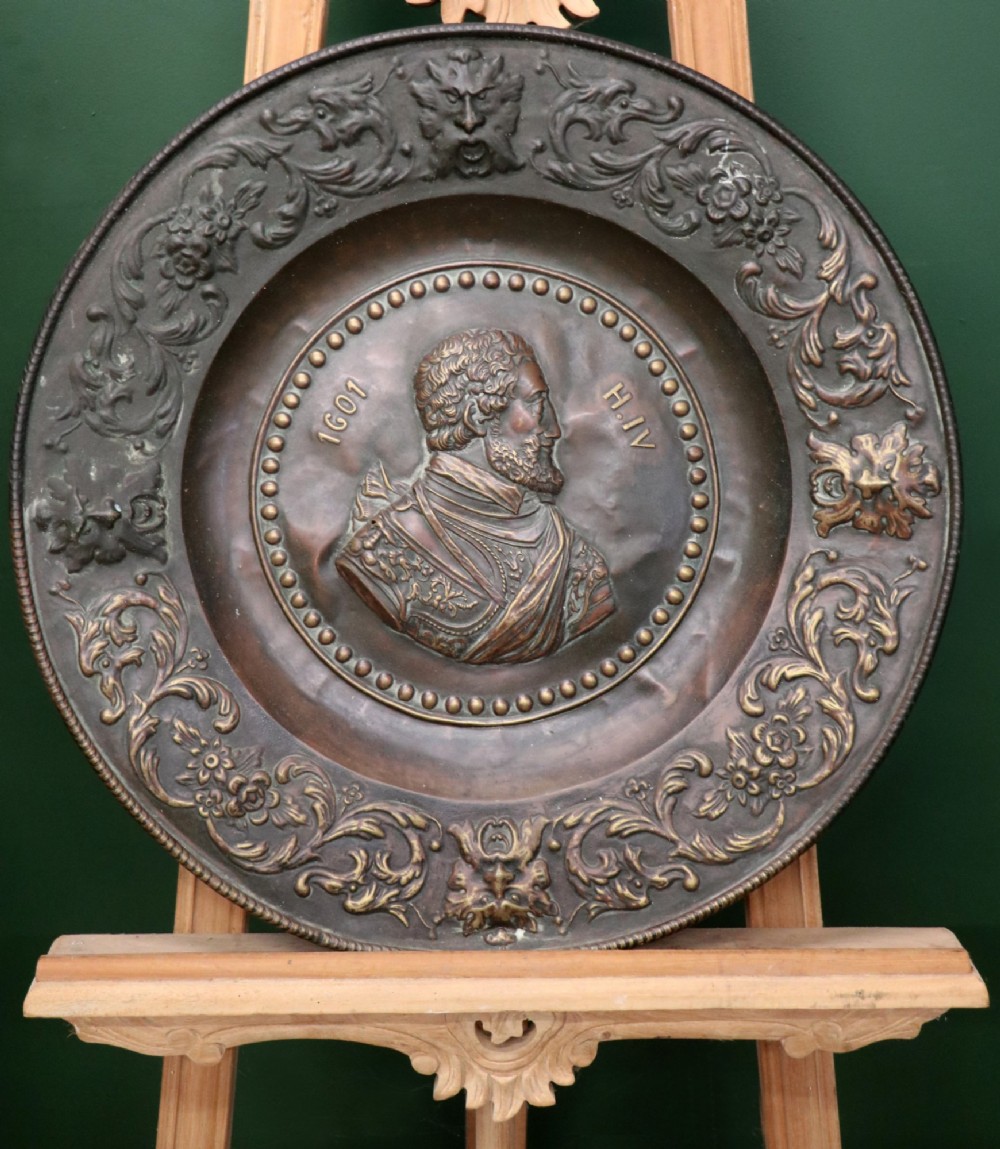 Pair of circular relief-embossed copper wall chargers depicting profile portraits of King Henry IV and Queen Marie de Medicis surrounded by floral and mask borders. View III