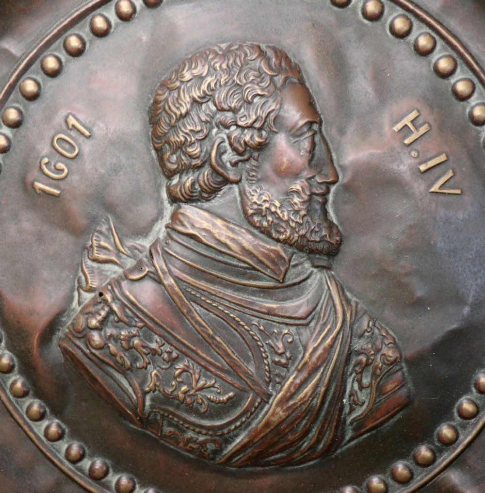 Pair of circular relief-embossed copper wall chargers depicting profile portraits of King Henry IV and Queen Marie de Medicis surrounded by floral and mask borders. View IV