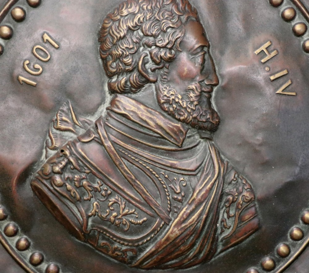 Pair of circular relief-embossed copper wall chargers depicting profile portraits of King Henry IV and Queen Marie de Medicis surrounded by floral and mask borders. View VI