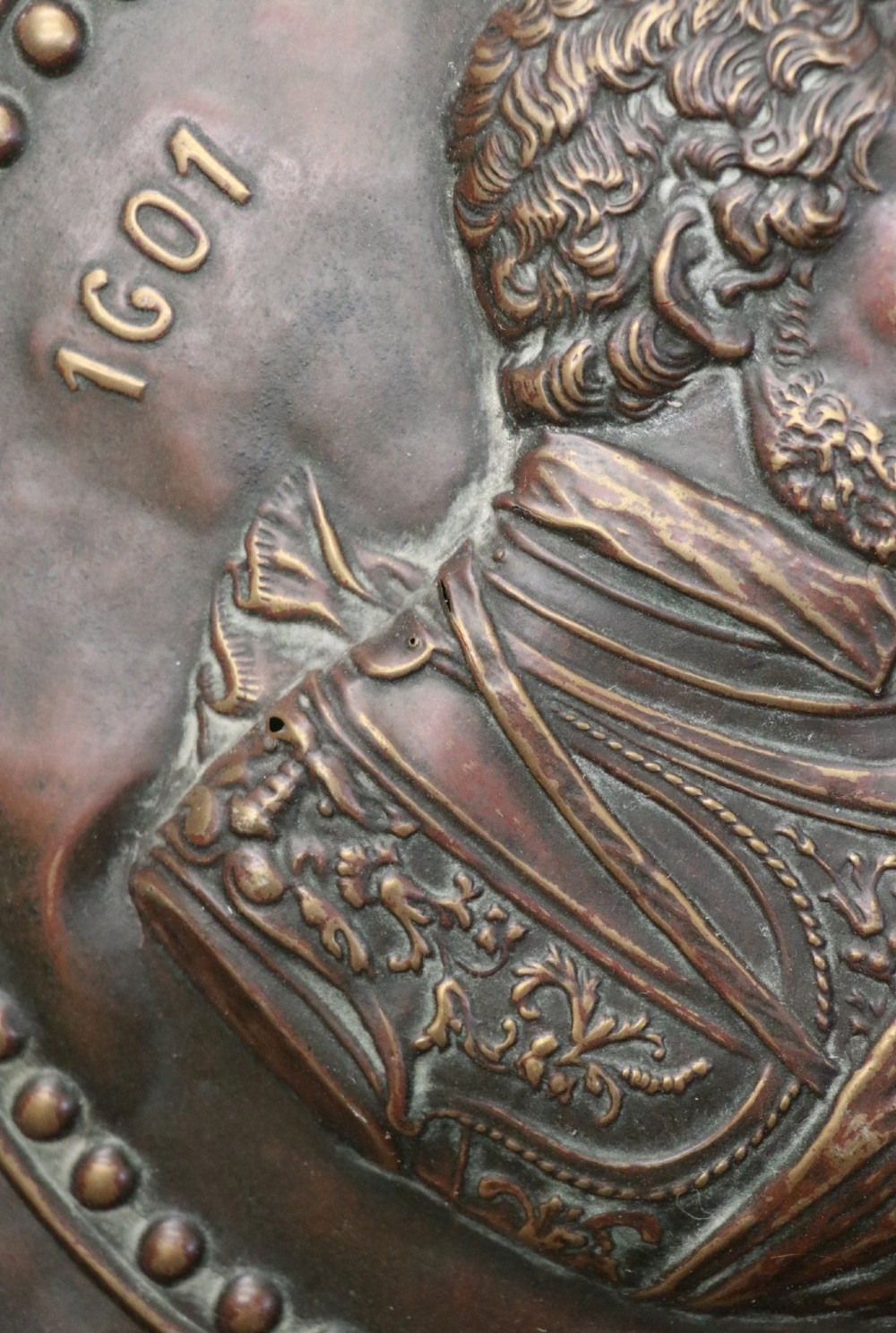 Pair of circular relief-embossed copper wall chargers depicting profile portraits of King Henry IV and Queen Marie de Medicis surrounded by floral and mask borders. View X
