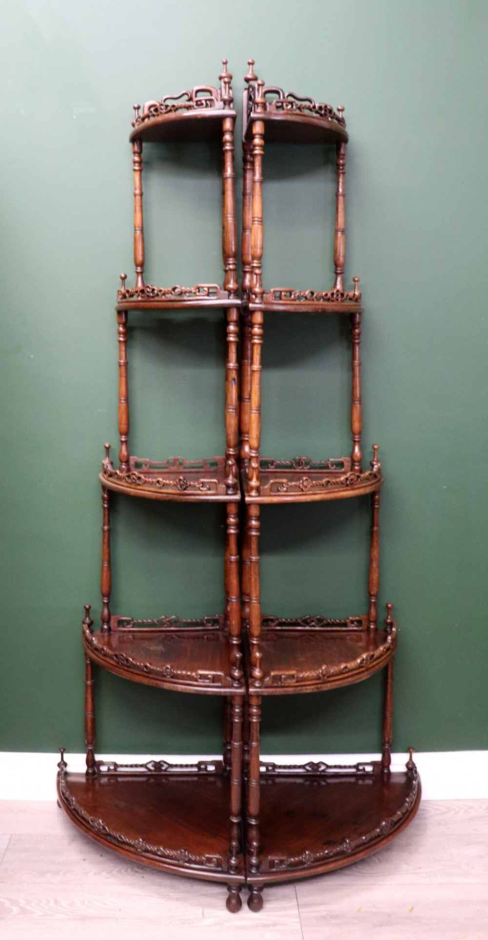 A matching pair of Victorian dark wood five-tier corner whatnots featuring turned spindle supports, carved pierced galleries, and decorative finials.