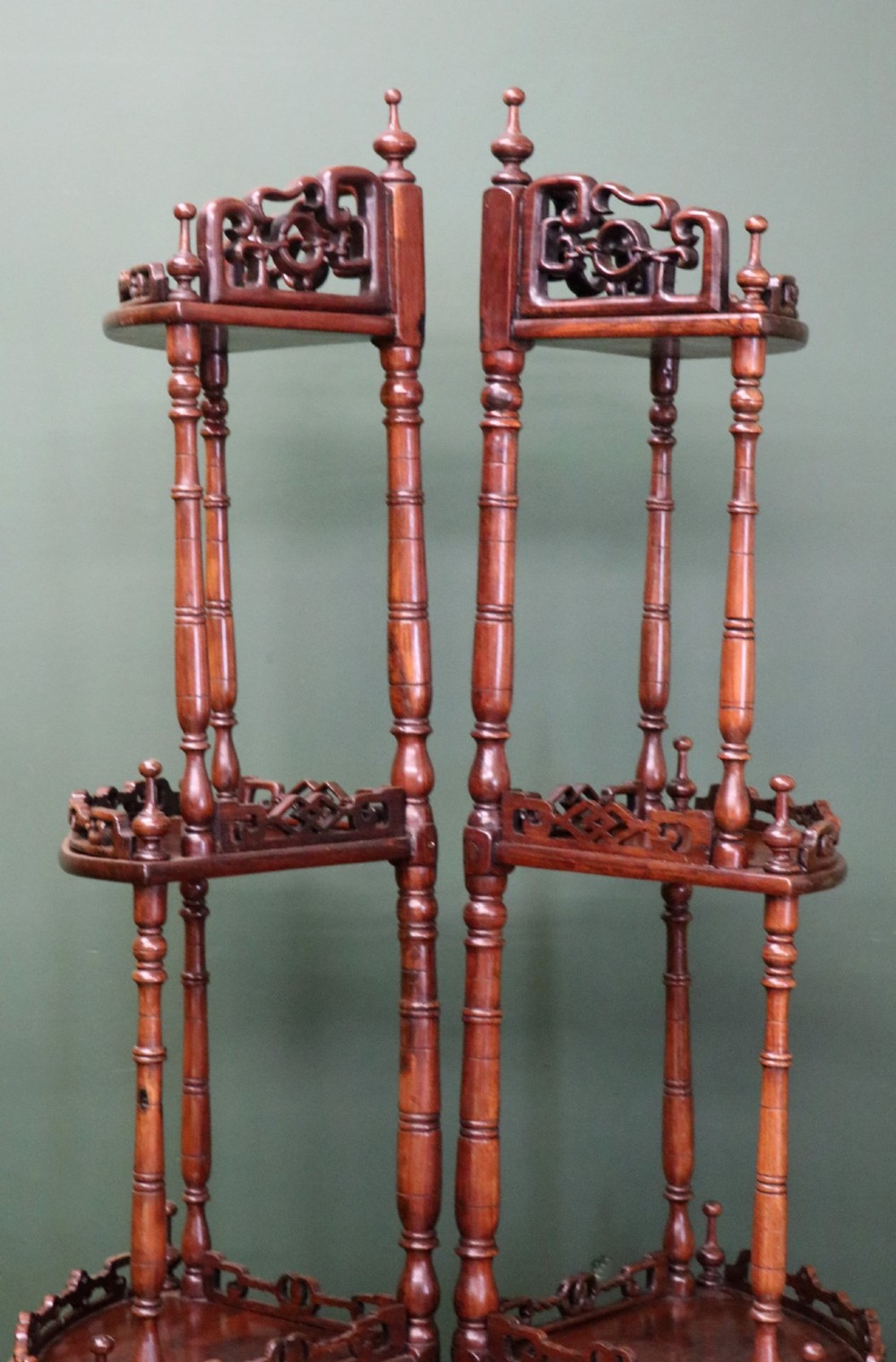 A matching pair of Victorian dark wood five-tier corner whatnots featuring turned spindle supports, carved pierced galleries, and decorative finials. View V