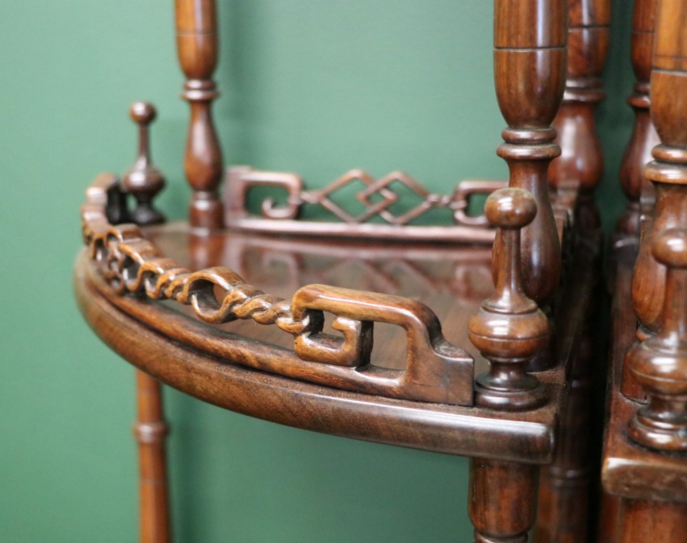 A matching pair of Victorian dark wood five-tier corner whatnots featuring turned spindle supports, carved pierced galleries, and decorative finials. View X