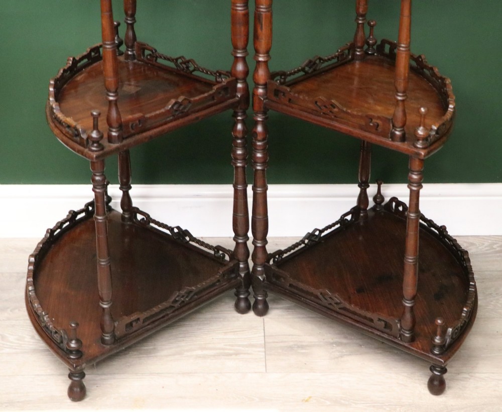 A matching pair of Victorian dark wood five-tier corner whatnots featuring turned spindle supports, carved pierced galleries, and decorative finials. View XV