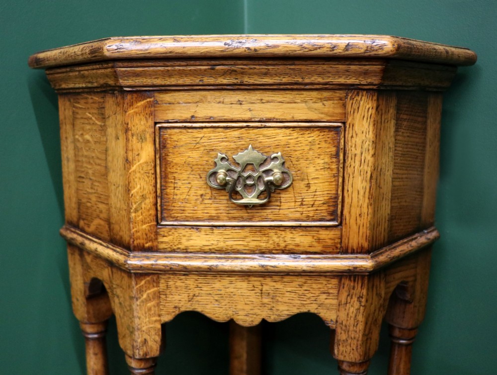 An antique golden oak corner table featuring turned legs, a single drawer with a brass drop handle, a shaped frieze, and a low tier shelf. View IX