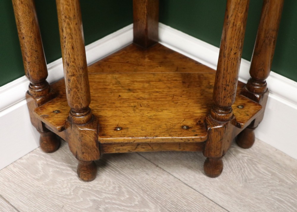 An antique golden oak corner table featuring turned legs, a single drawer with a brass drop handle, a shaped frieze, and a low tier shelf. View XV