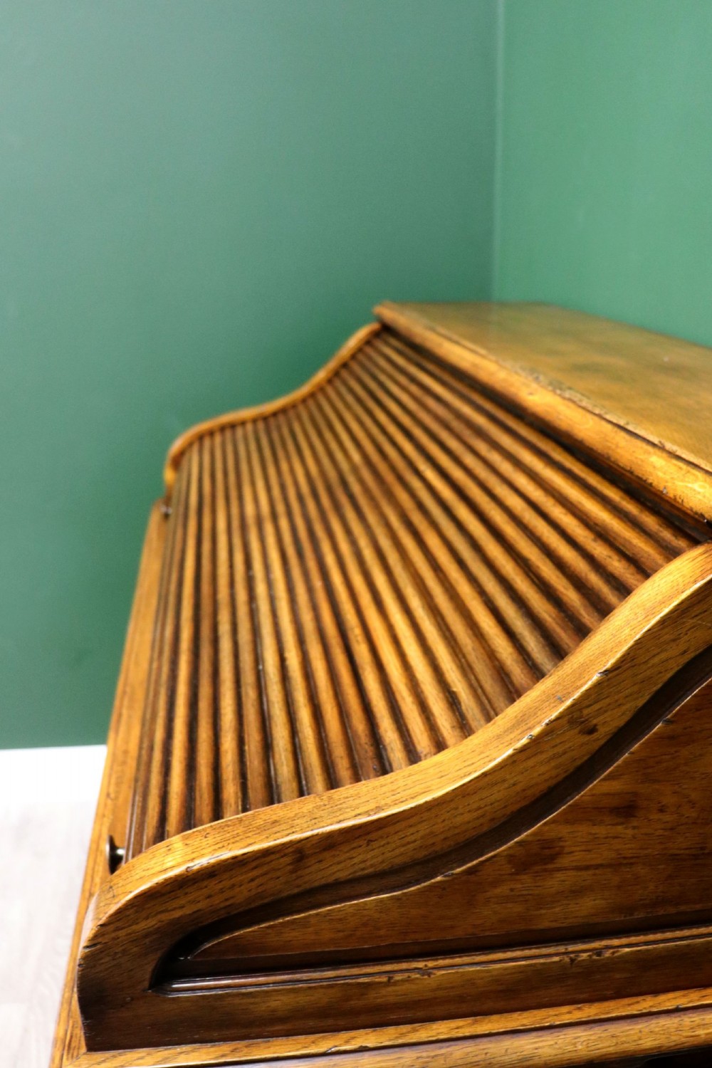 A solid oak roll top desk featuring a retracted slatted tambour top revealing a fitted interior with small drawers and pigeonholes over twin pedestals. View IX