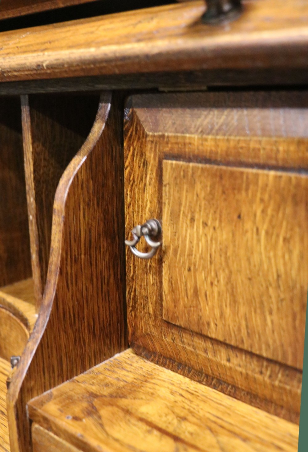 A solid oak roll top desk featuring a retracted slatted tambour top revealing a fitted interior with small drawers and pigeonholes over twin pedestals. View XII