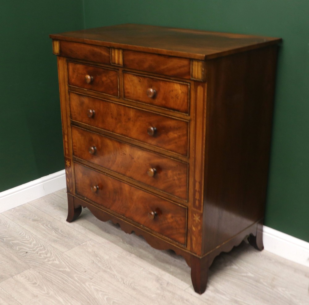 A small Victorian mahogany chest of drawers featuring decorative inlay along the frame, turned wooden knobs, and a shaped apron on curved feet. View V