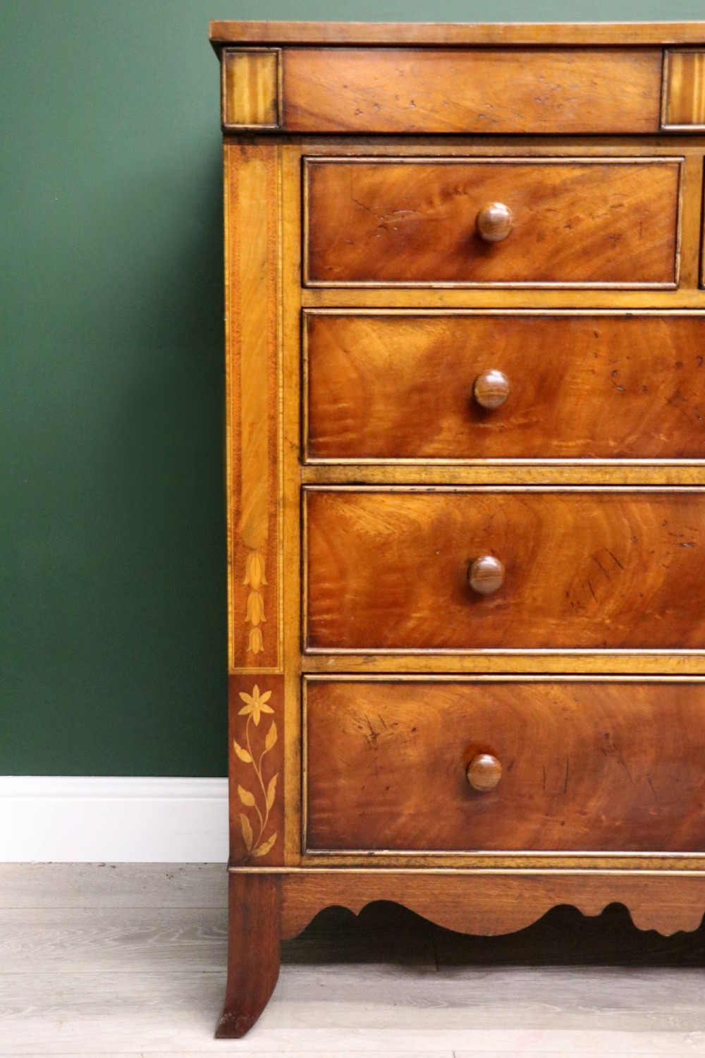 A small Victorian mahogany chest of drawers featuring decorative inlay along the frame, turned wooden knobs, and a shaped apron on curved feet. View X