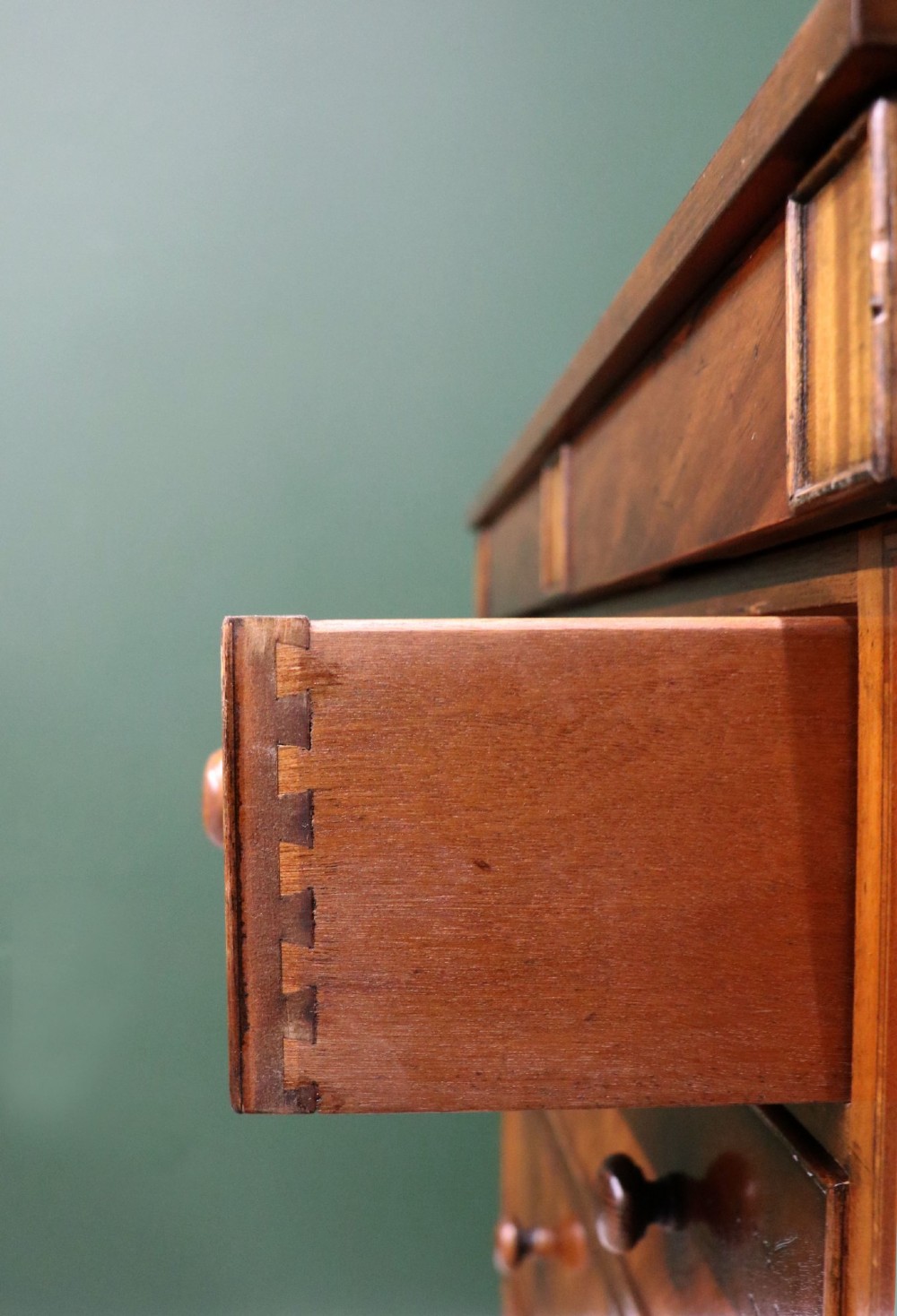 A small Victorian mahogany chest of drawers featuring decorative inlay along the frame, turned wooden knobs, and a shaped apron on curved feet. View XI