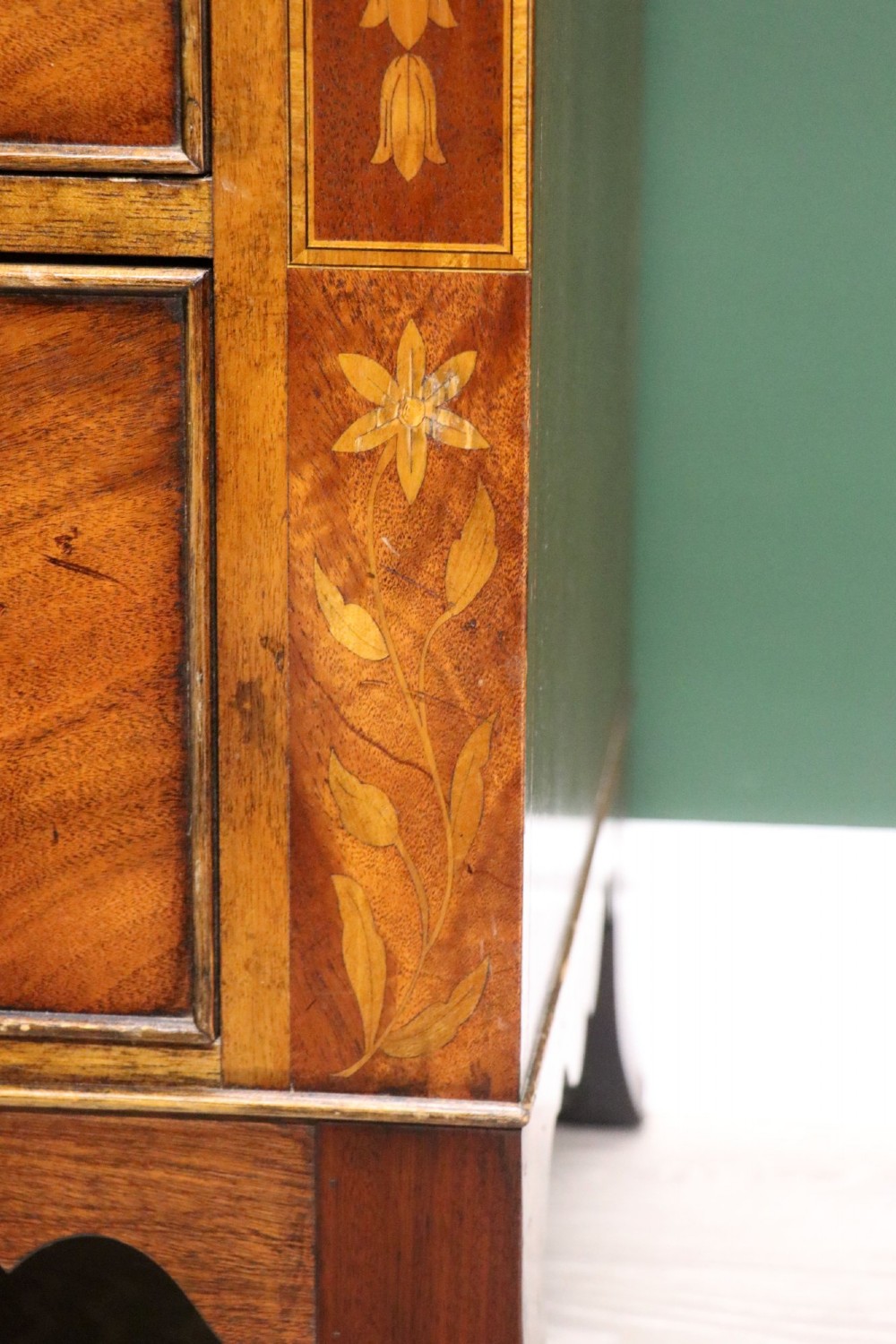 A small Victorian mahogany chest of drawers featuring decorative inlay along the frame, turned wooden knobs, and a shaped apron on curved feet. View XV