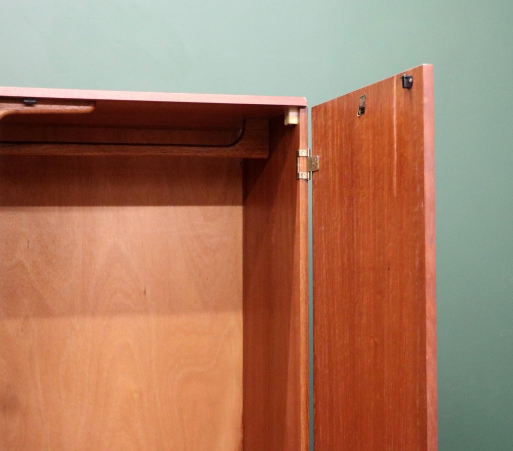 A mid-century teak wood wardrobe featuring two doors with rectangular wooden handles, short tapered legs, and a narrow central full-length mirror. View IX
