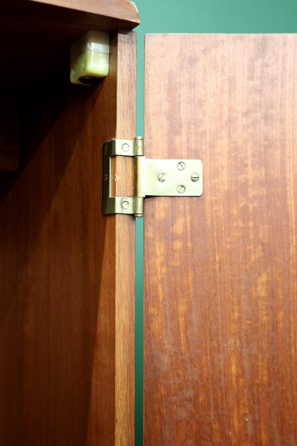 A mid-century teak wood wardrobe featuring two doors with rectangular wooden handles, short tapered legs, and a narrow central full-length mirror. View X