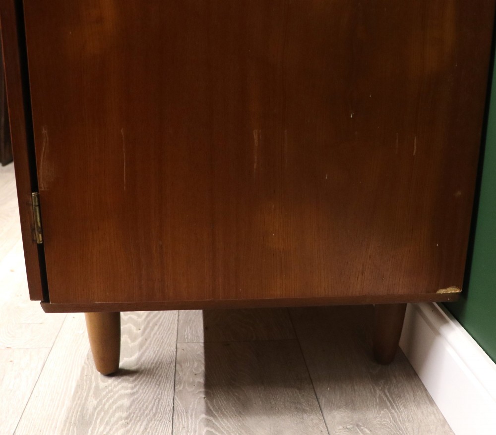 A mid-century teak wood wardrobe featuring two doors with rectangular wooden handles, short tapered legs, and a narrow central full-length mirror. View XIV