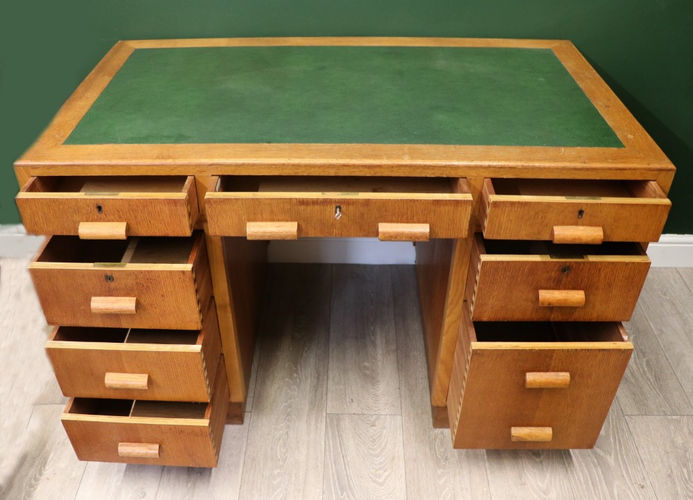 An Art Deco light oak twin pedestal desk featuring a green writing top inset and carved wooden bar drawer handles. View III