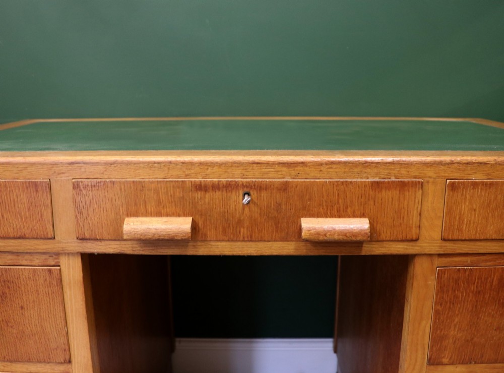 An Art Deco light oak twin pedestal desk featuring a green writing top inset and carved wooden bar drawer handles. View VIII