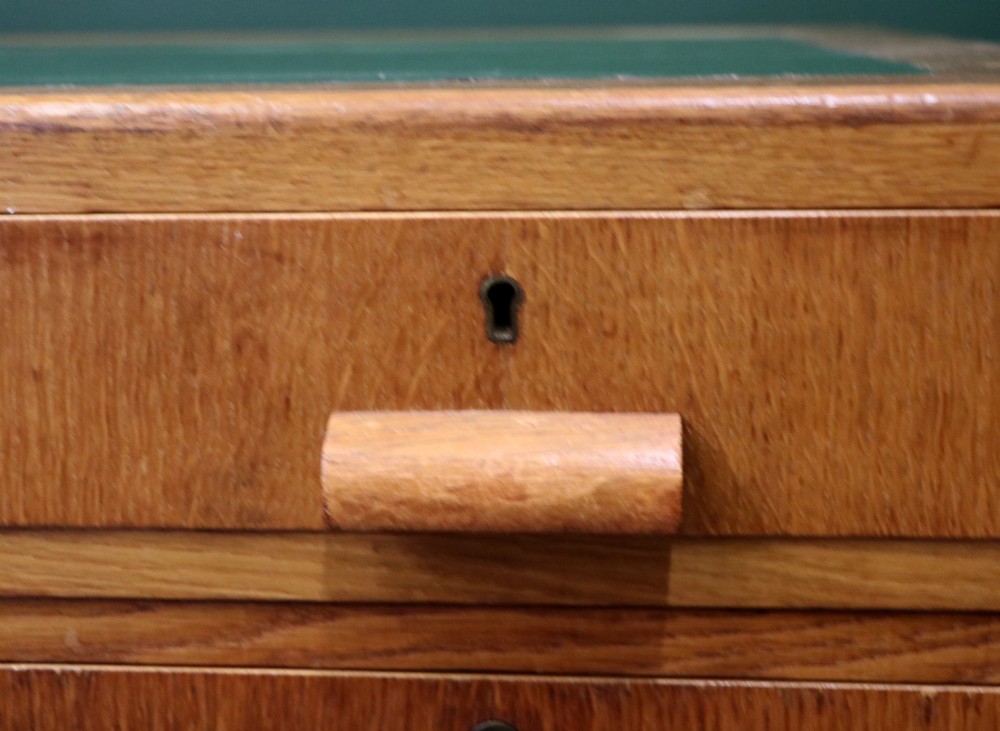 An Art Deco light oak twin pedestal desk featuring a green writing top inset and carved wooden bar drawer handles. View XI