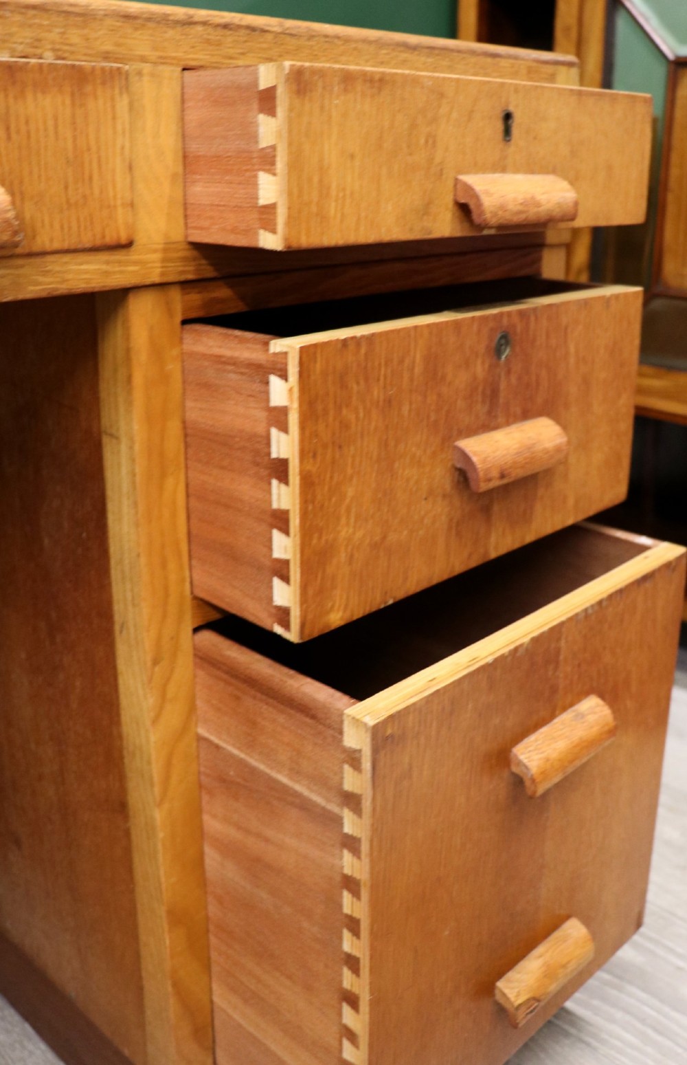 An Art Deco light oak twin pedestal desk featuring a green writing top inset and carved wooden bar drawer handles. View XII