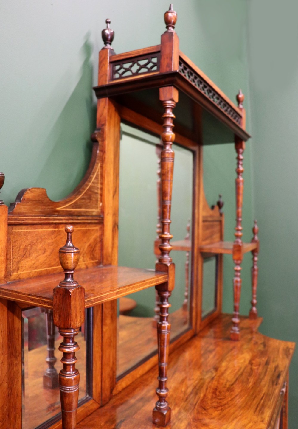 A late Victorian wooden credenza featuring a central inlaid cupboard door, open side shelves, turned spindle pillars, and a multi-pane mirrored back with a fretwork gallery top. View IV