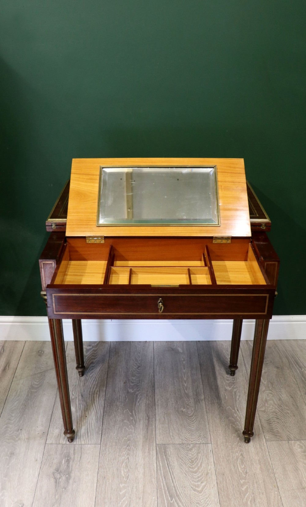 A late nineteenth-century French wooden vanity table featuring an open hinged lid with a mirror, interior satinwood compartments, and slender fluted legs.