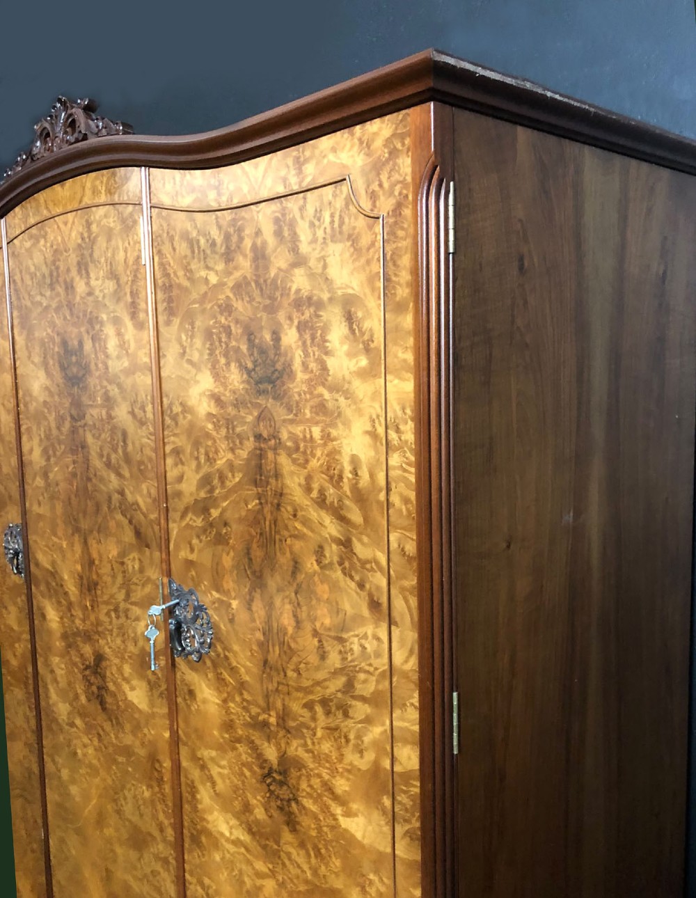 A large Queen Anne revival three-door wardrobe crafted with highly figured burr walnut veneer, featuring carved cresting and decorative metal escutcheons. View VIII