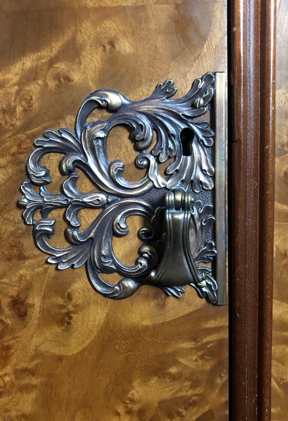 A large Queen Anne revival three-door wardrobe crafted with highly figured burr walnut veneer, featuring carved cresting and decorative metal escutcheons. View IX