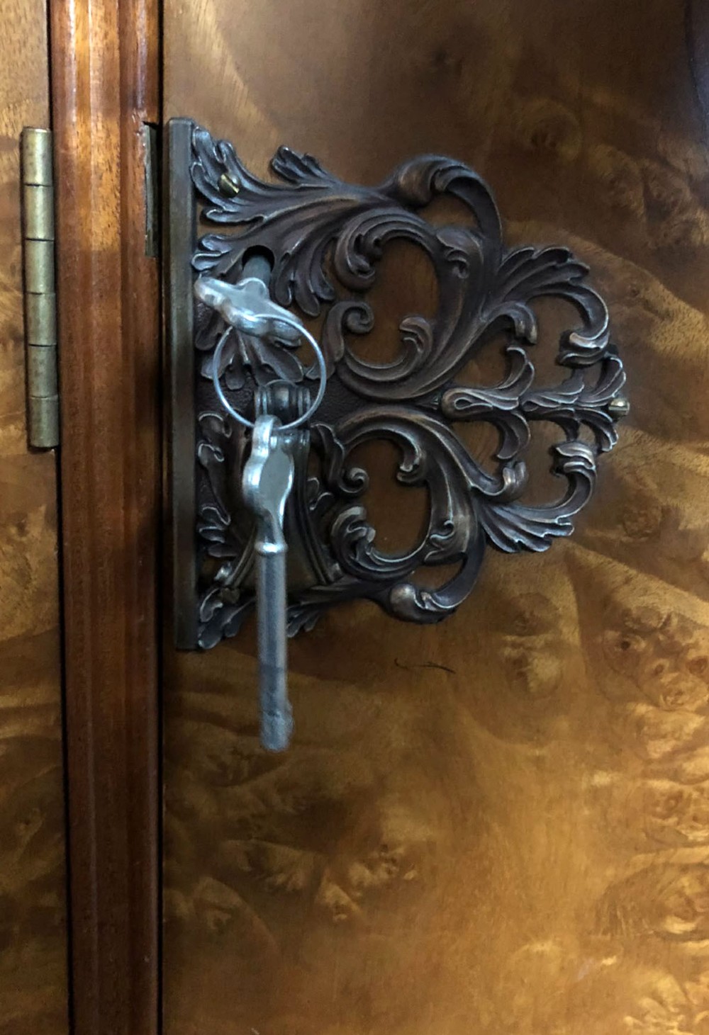 A large Queen Anne revival three-door wardrobe crafted with highly figured burr walnut veneer, featuring carved cresting and decorative metal escutcheons. View X