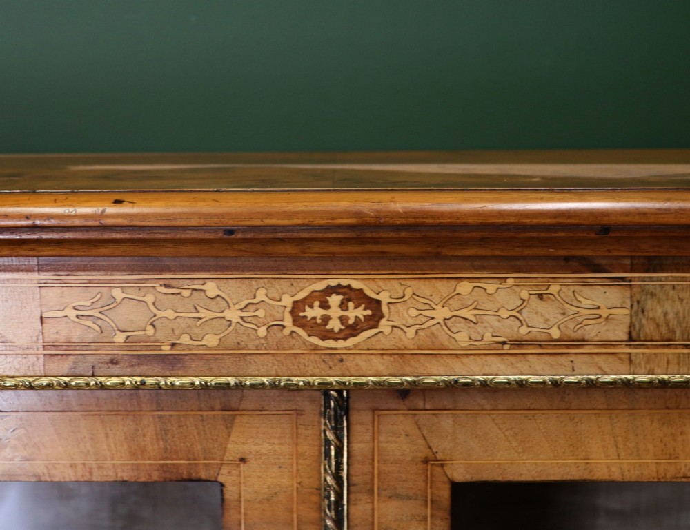 A mid-Victorian low walnut veneered bookcase featuring two glass glazed doors, marquetry inlay along the frieze, and brass trim detailing. View VII