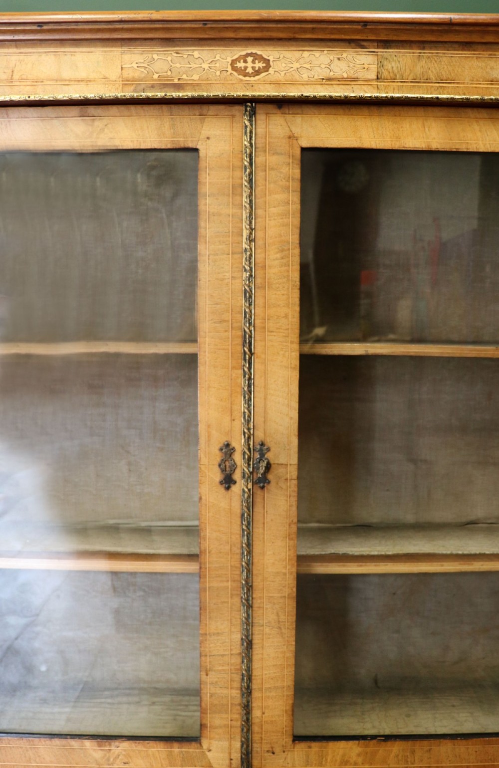 A mid-Victorian low walnut veneered bookcase featuring two glass glazed doors, marquetry inlay along the frieze, and brass trim detailing. View VIII