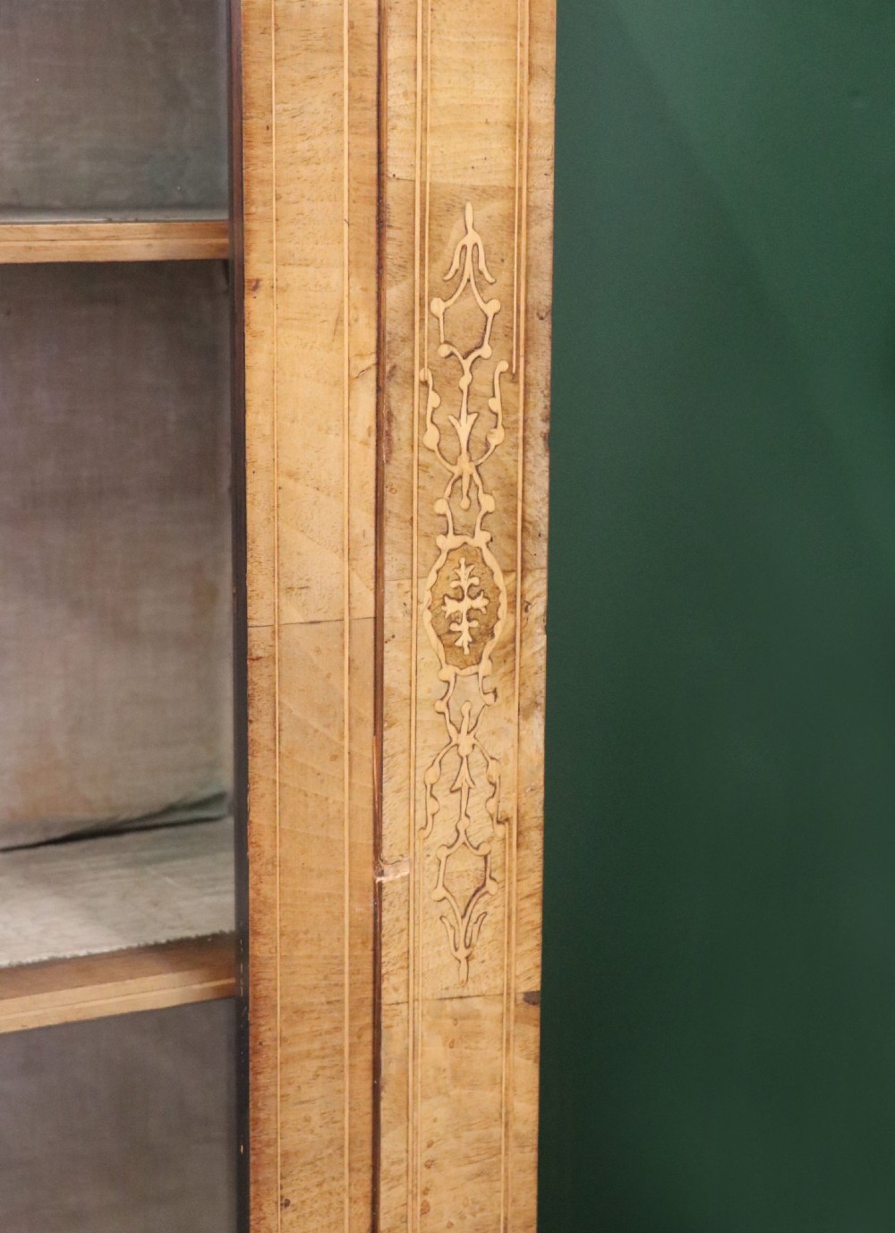 A mid-Victorian low walnut veneered bookcase featuring two glass glazed doors, marquetry inlay along the frieze, and brass trim detailing. View X
