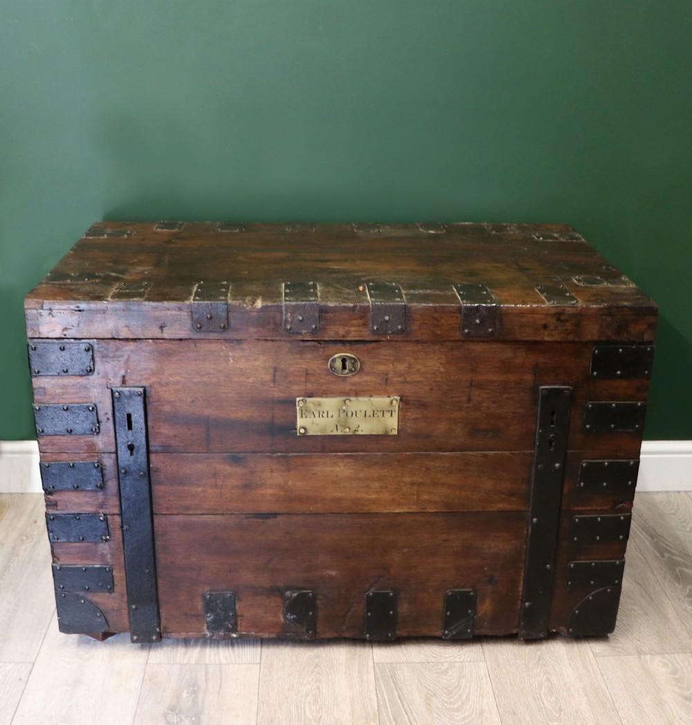 A 19th-century dark oak storage chest reinforced with black iron strapping and featuring a central brass plaque.