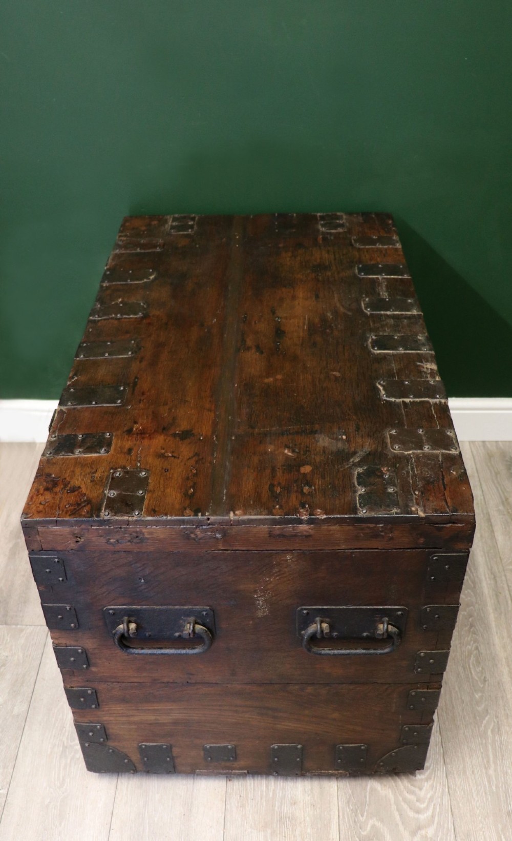 A 19th-century dark oak storage chest reinforced with black iron strapping and featuring a central brass plaque. View III