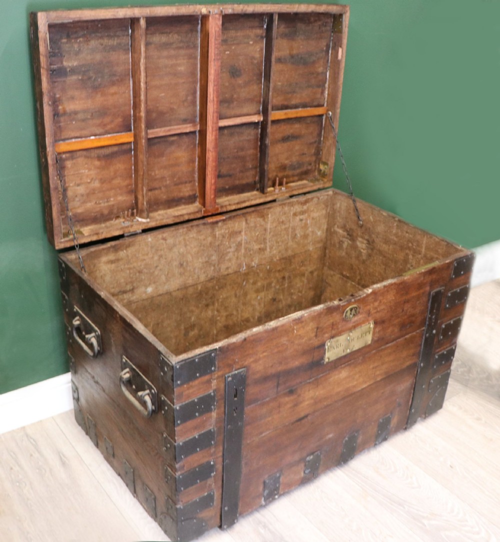 A 19th-century dark oak storage chest reinforced with black iron strapping and featuring a central brass plaque. View V