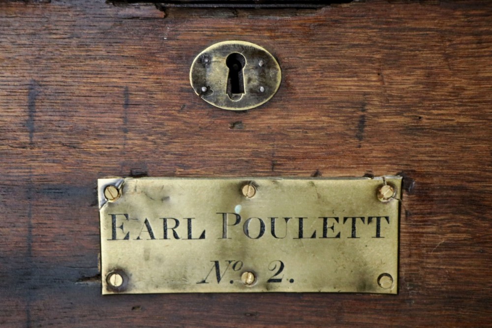 A 19th-century dark oak storage chest reinforced with black iron strapping and featuring a central brass plaque. View VI