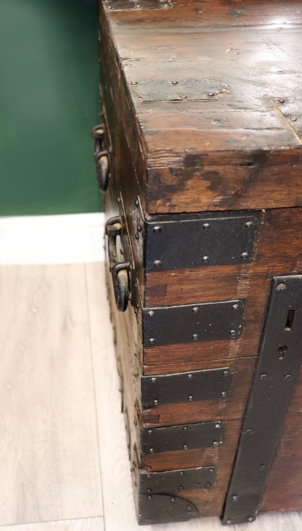 A 19th-century dark oak storage chest reinforced with black iron strapping and featuring a central brass plaque. View VIII