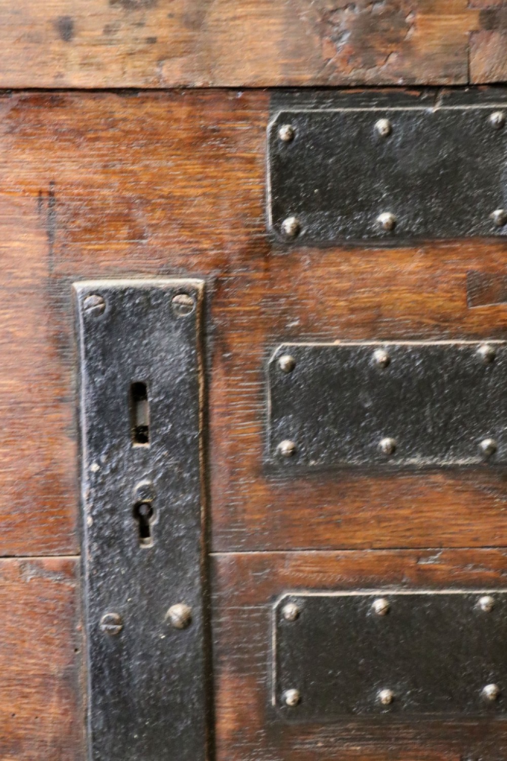 A 19th-century dark oak storage chest reinforced with black iron strapping and featuring a central brass plaque. View X